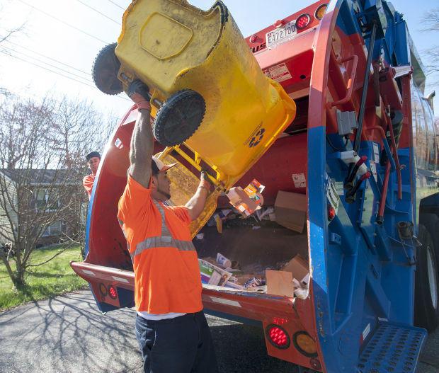 Man emptying yellow recycling cart into recycling truck.
