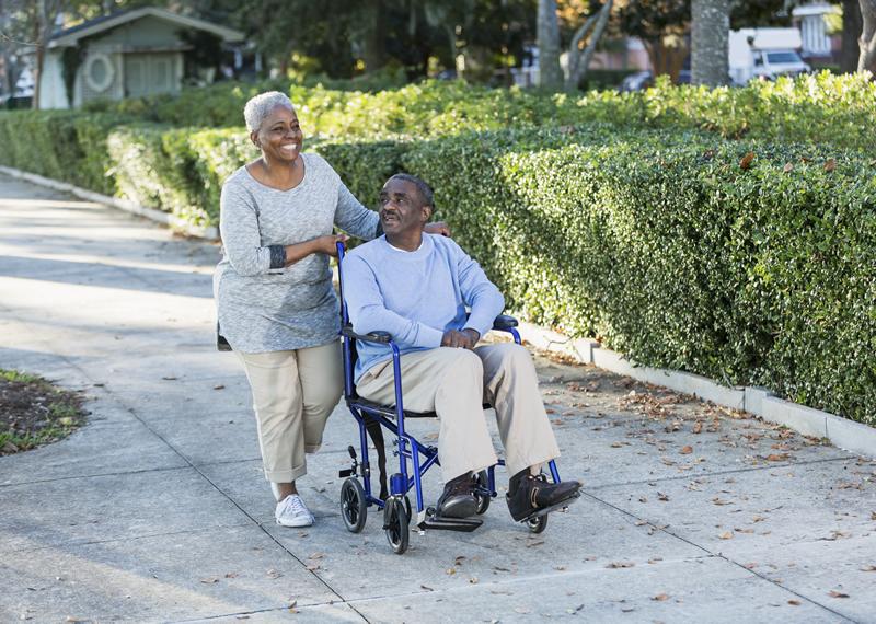 Lady pushing man in wheelchair