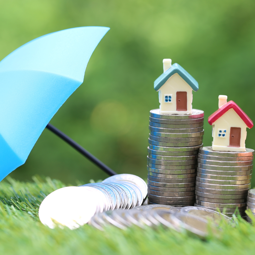 money and miniature houses protected by umbrella