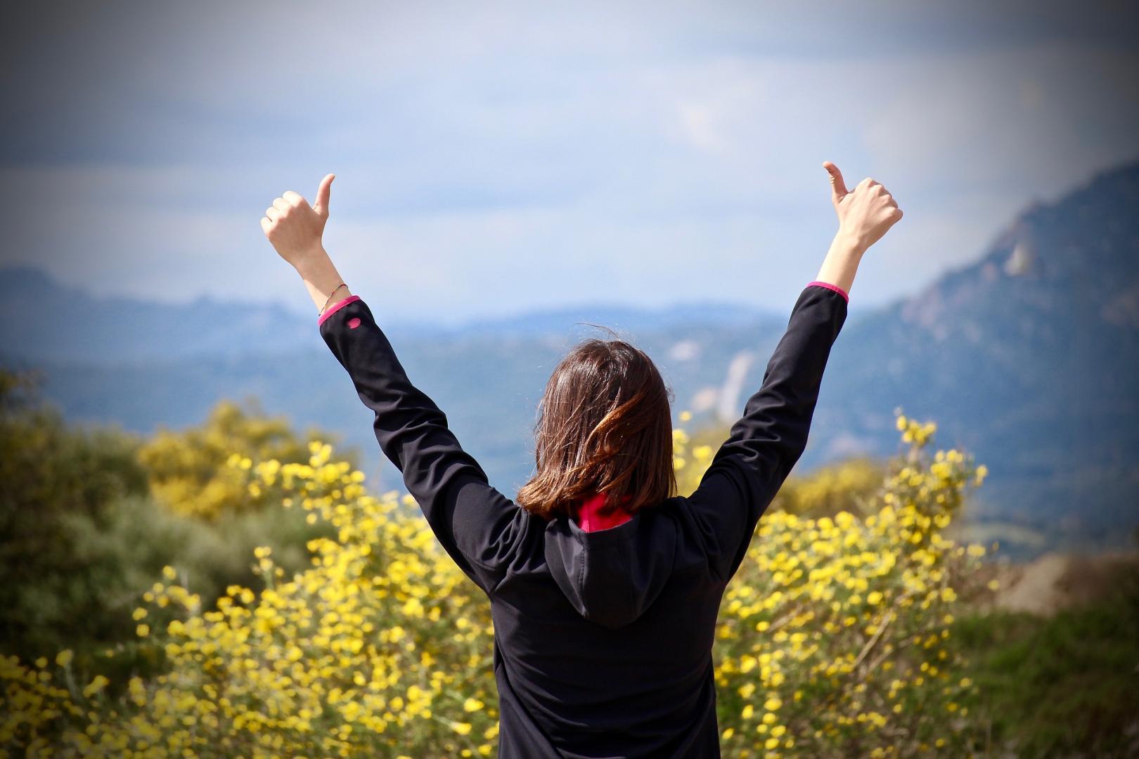 Woman holding her arms in the air with thumbs up