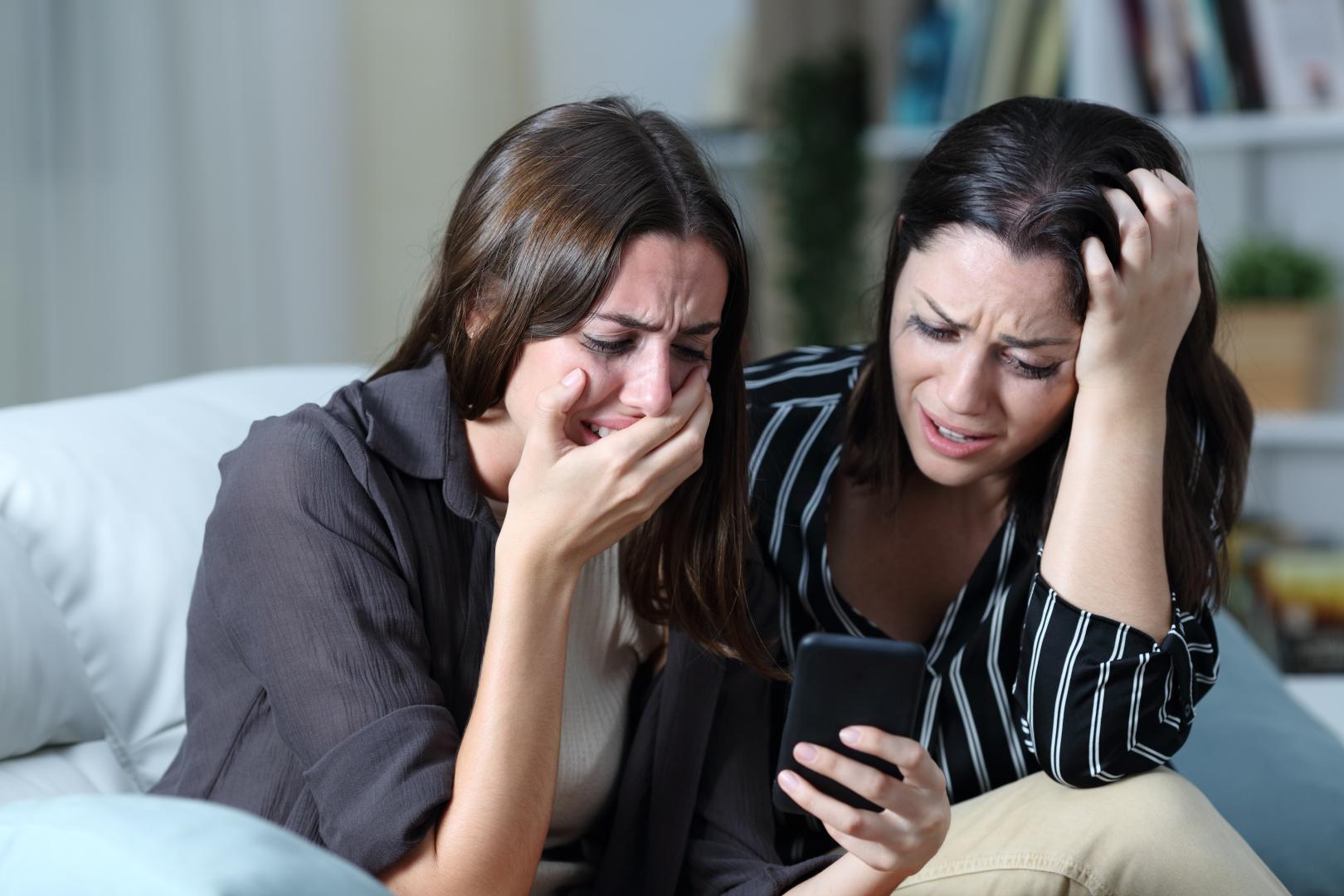 Two Girls Crying Looking at Phone