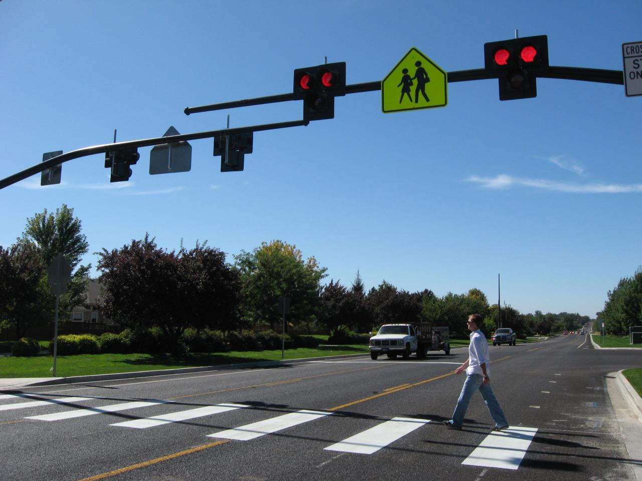 A man crossing a crosswalk through a multi-lane intersection