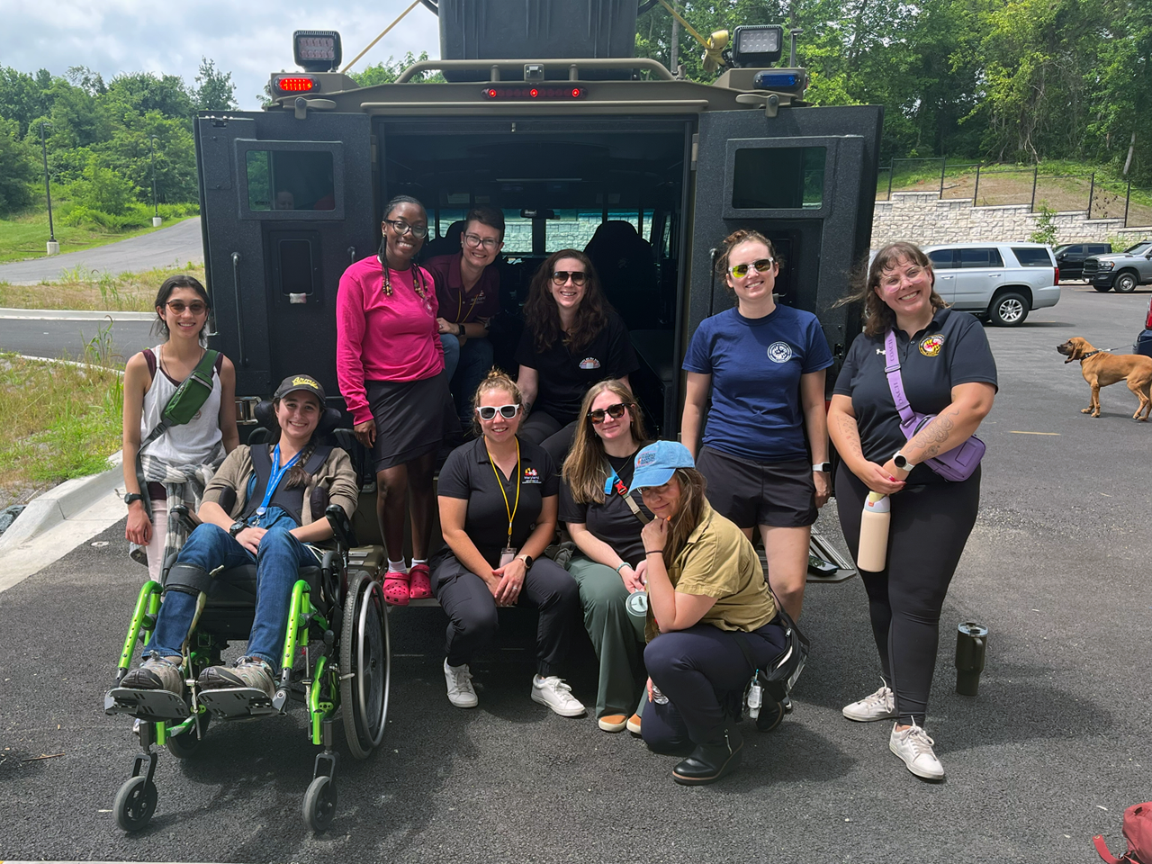 Group of women outside in front of military vehicle