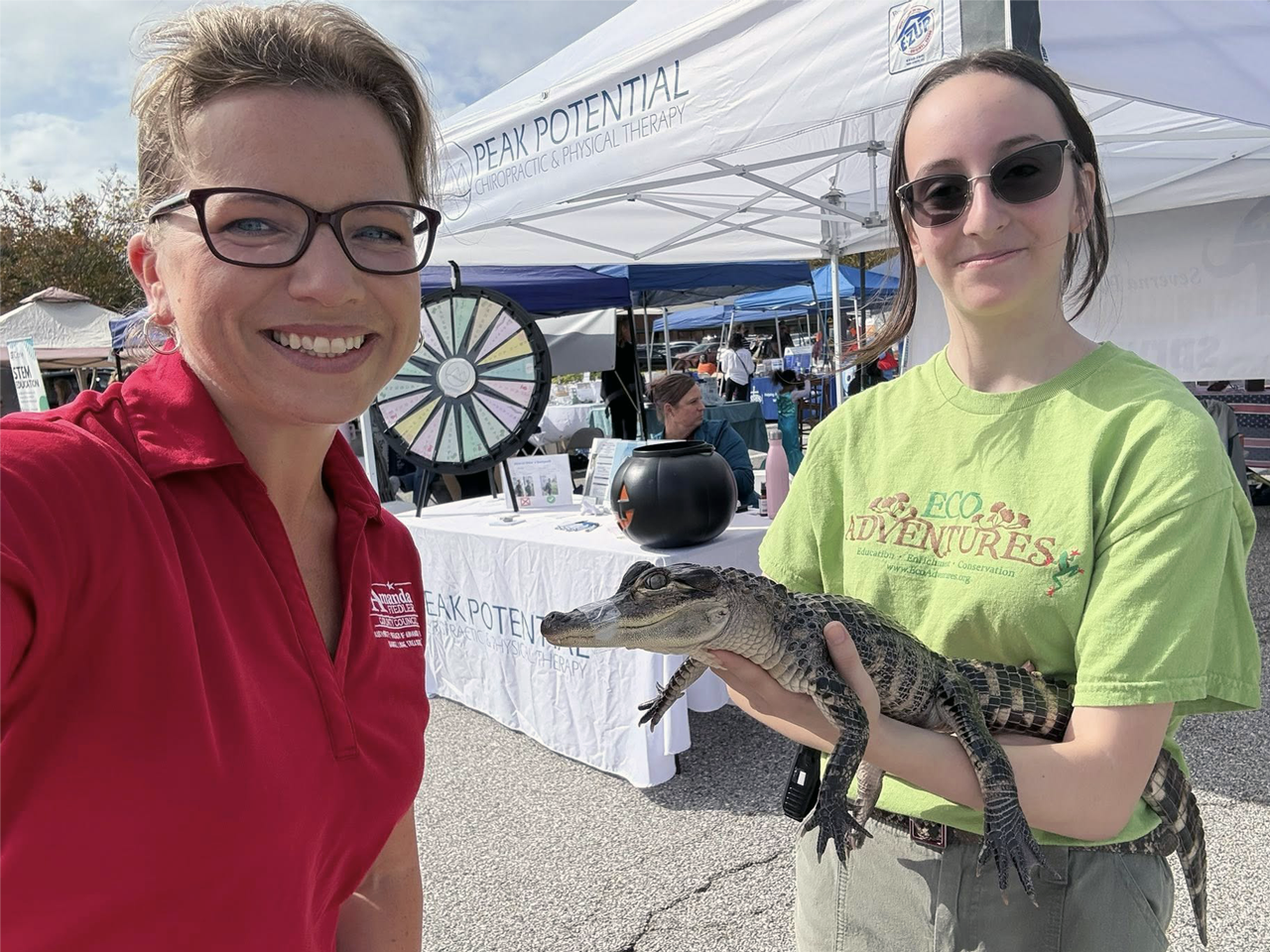 Two women with one woman holding a reptile