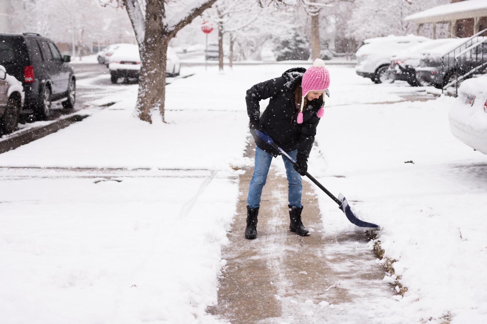 Young woman shoveling snow stock photo