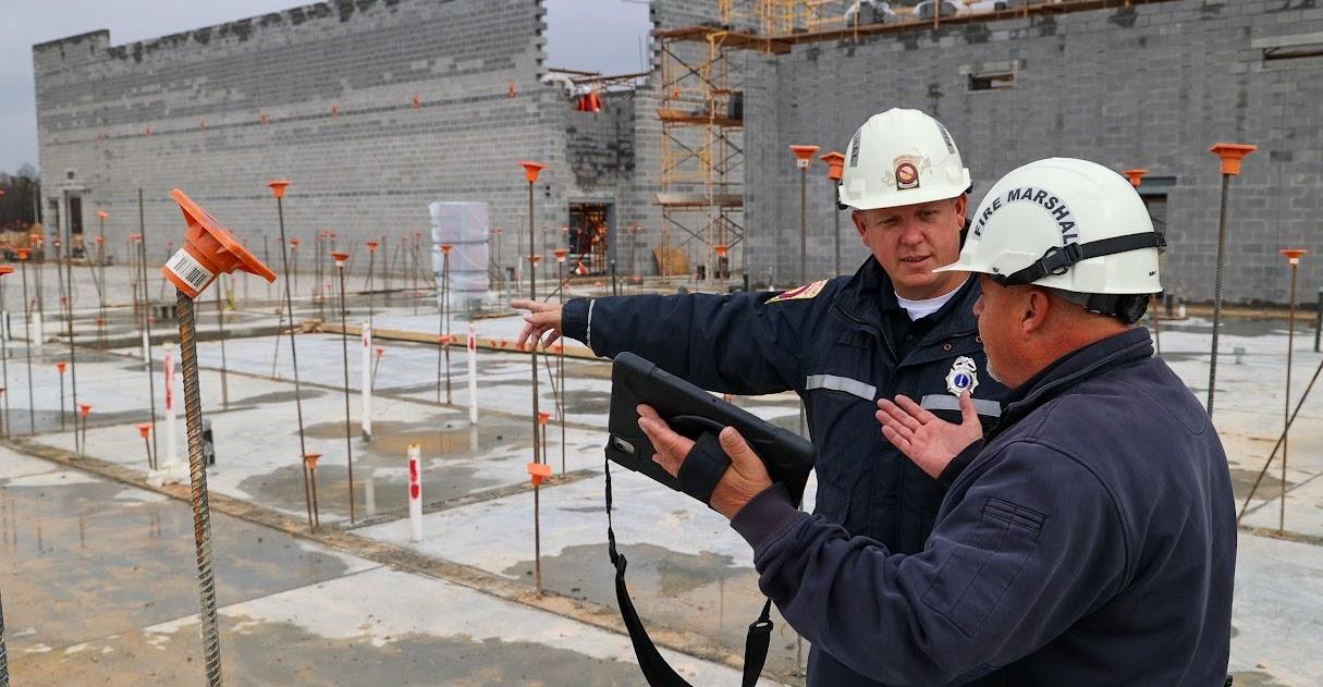 Two men wearing white safety helmets talking