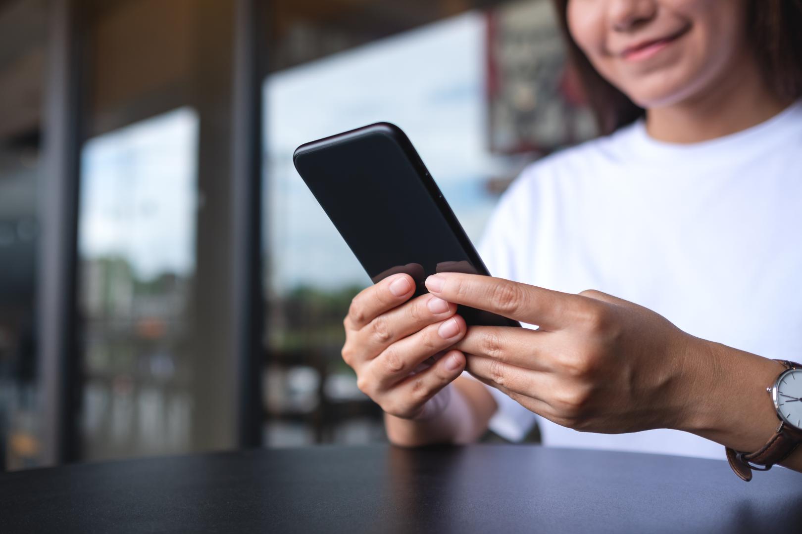 A young woman holding and using mobile phone
