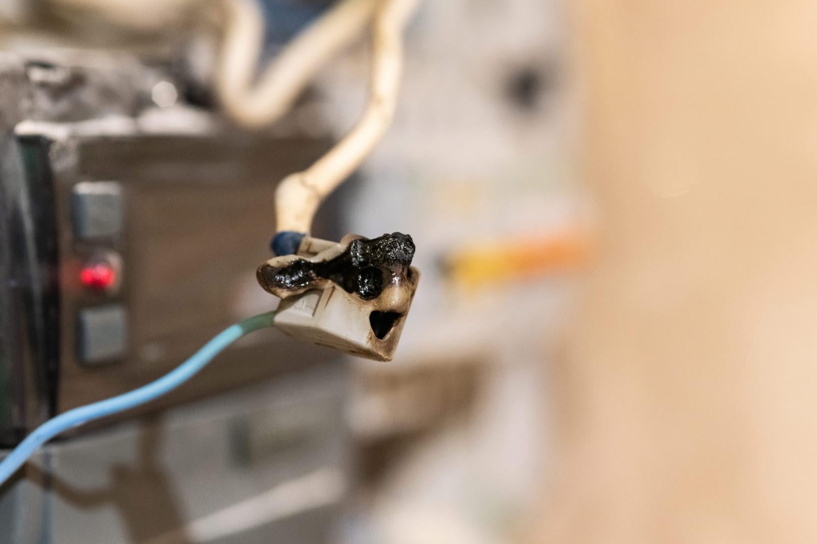 Burned wire, splicing connector, electrical terminal block of nonflammable, fireproof material. Faulty wiring or negligent electrical work. Dangerous short circuit accident. stock photo