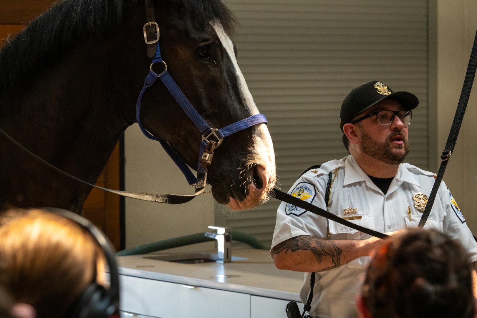 Person wearing a park police uniform standing with a horse talking to the participants at the HERoes on the HERizon Camp