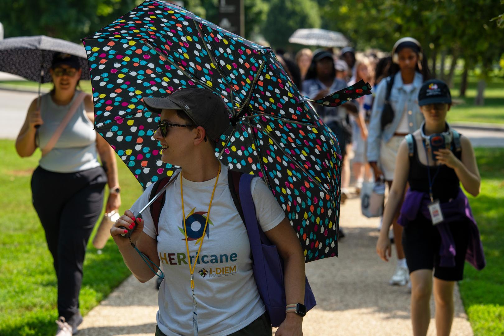 Participants walking with umbrellas during HERoes on the HERizon Camp