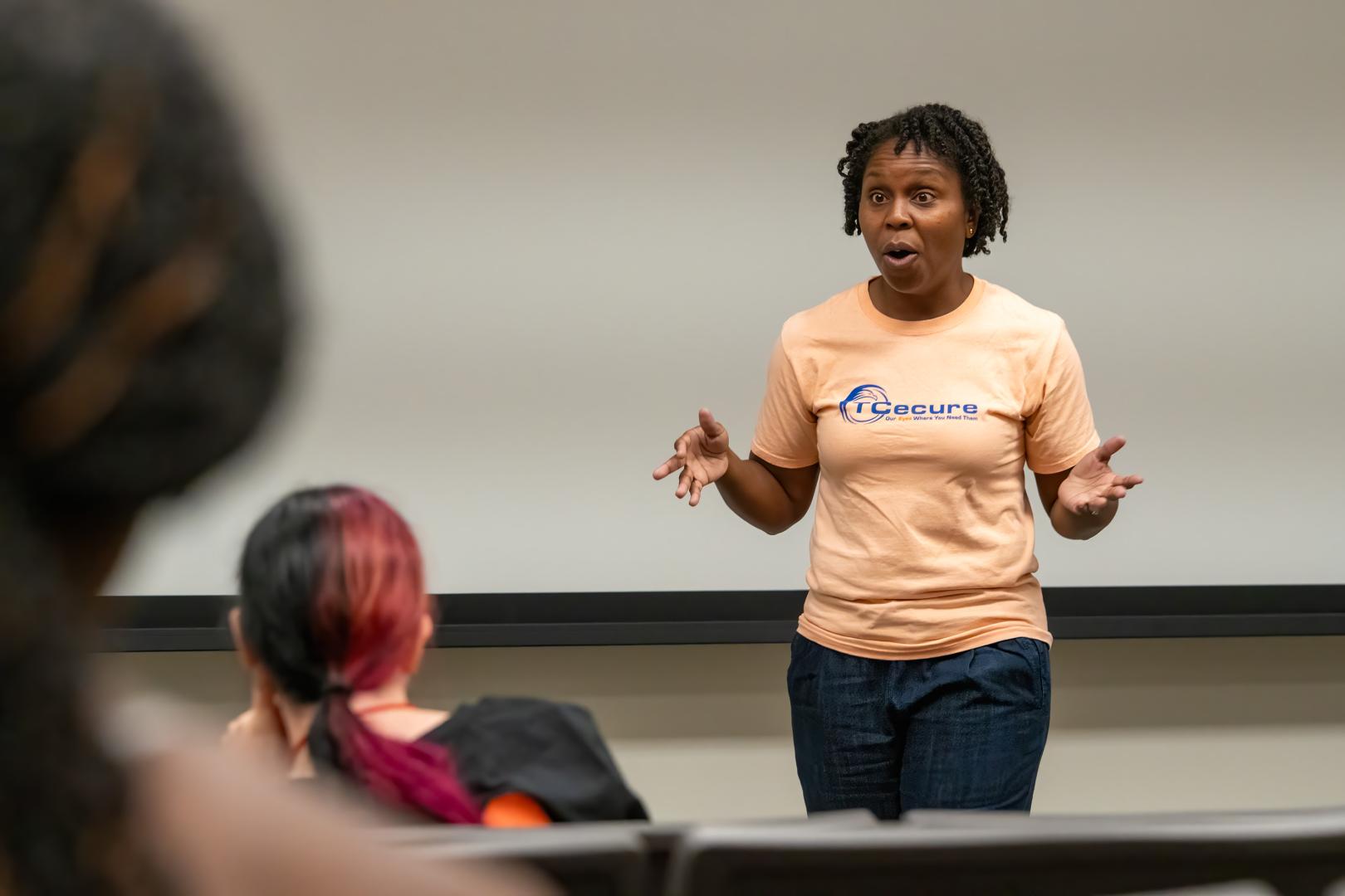 A speaker addressing a group of campers sitting in an audience at the HERoes on the HERizon leadership event