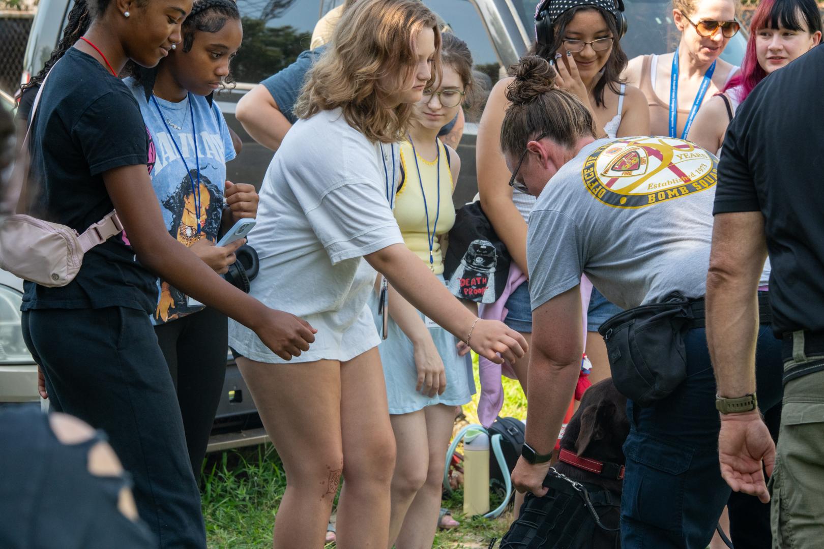 A group of young women participating in a team-building activity at the HERoes on the HERizon camp, engaged and smiling outdoors