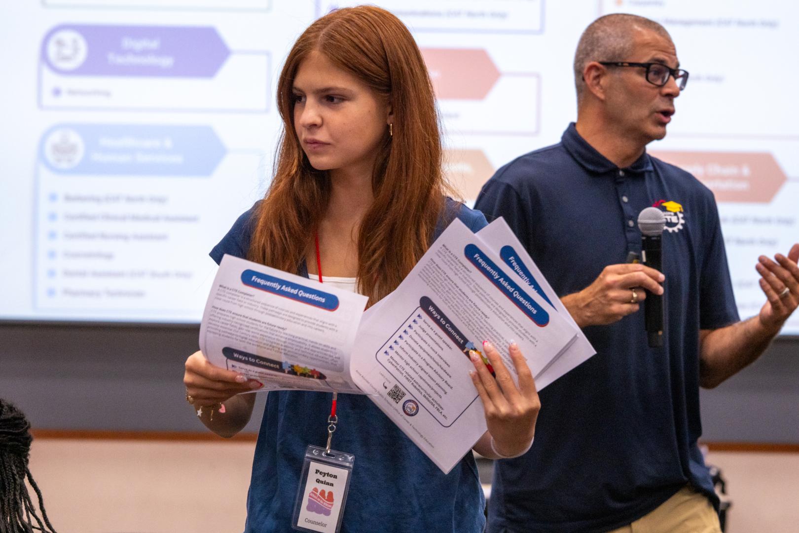 A speaker handing participants flyers at the HERoes on the HERizon leadership event
