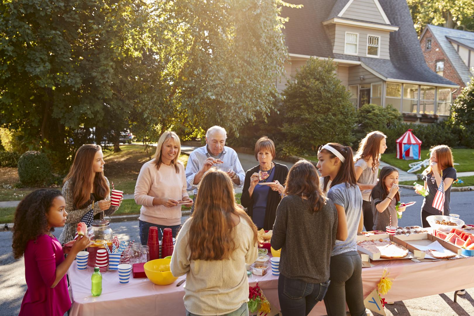 Neighbors talk and eat around a table at a block party stock photo